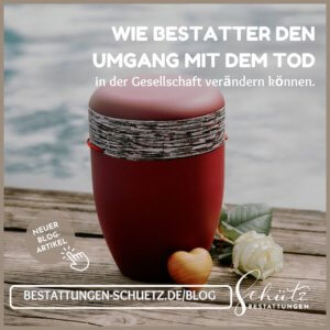 Rote Urne mit einer grau-weiß-schwarzen Banderole, daneben ein Holzherz und eine weiße Rose auf einem Steg mit Wasser im Hintergrund. Auf dem Bild sind das Logo von Schütz Bestattungen und ein Verweis auf den Blogbeitrag "Wie Bestatter den Umgang mit dem Tod in der Gesellschaft verändern können" zu sehen.